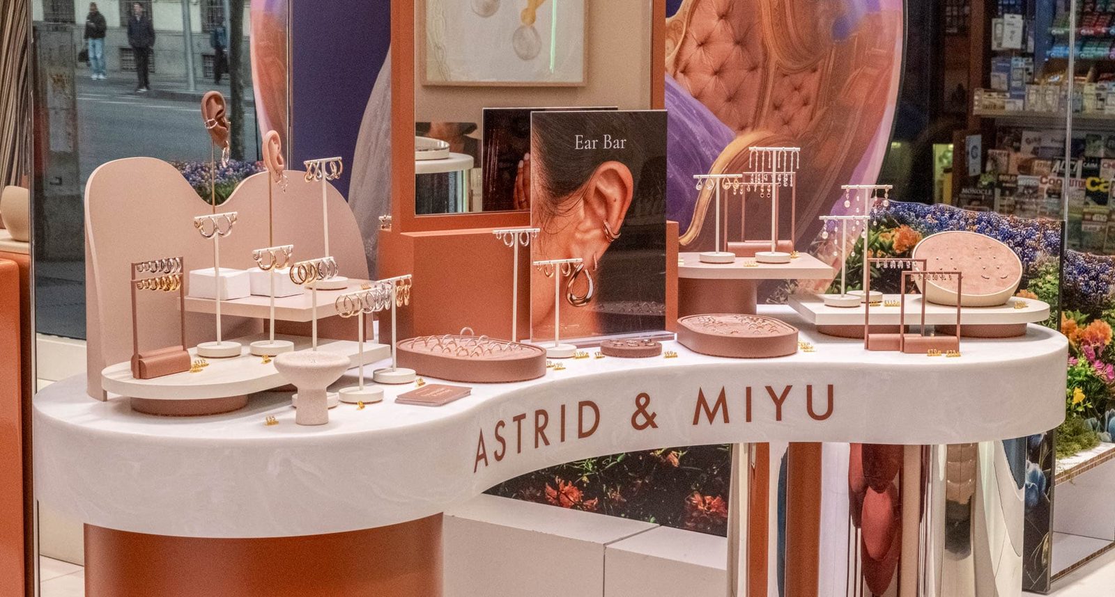 Expositor elegante de joyería en el evento de lanzamiento de Astrid & Miyu en Madrid, con collares, pendientes y anillos sobre soportes de marca.
