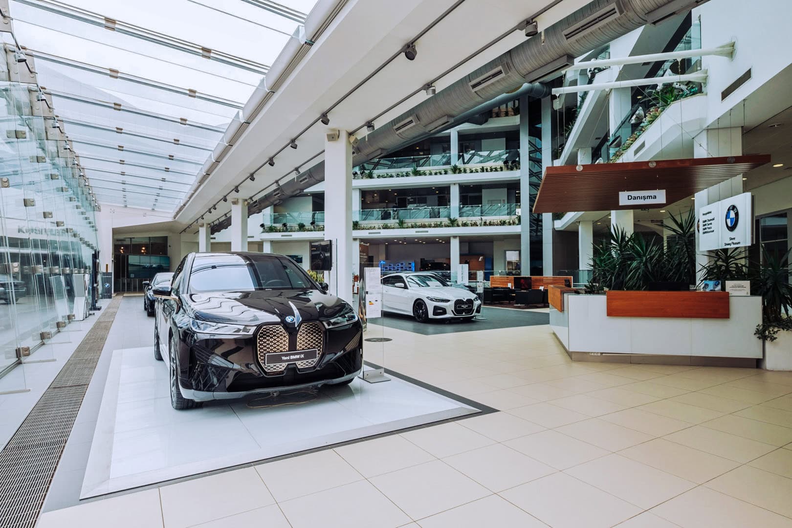 Interior de un concesionario BMW con un vehículo sobre suelo pulido bajo iluminación arquitectónica.