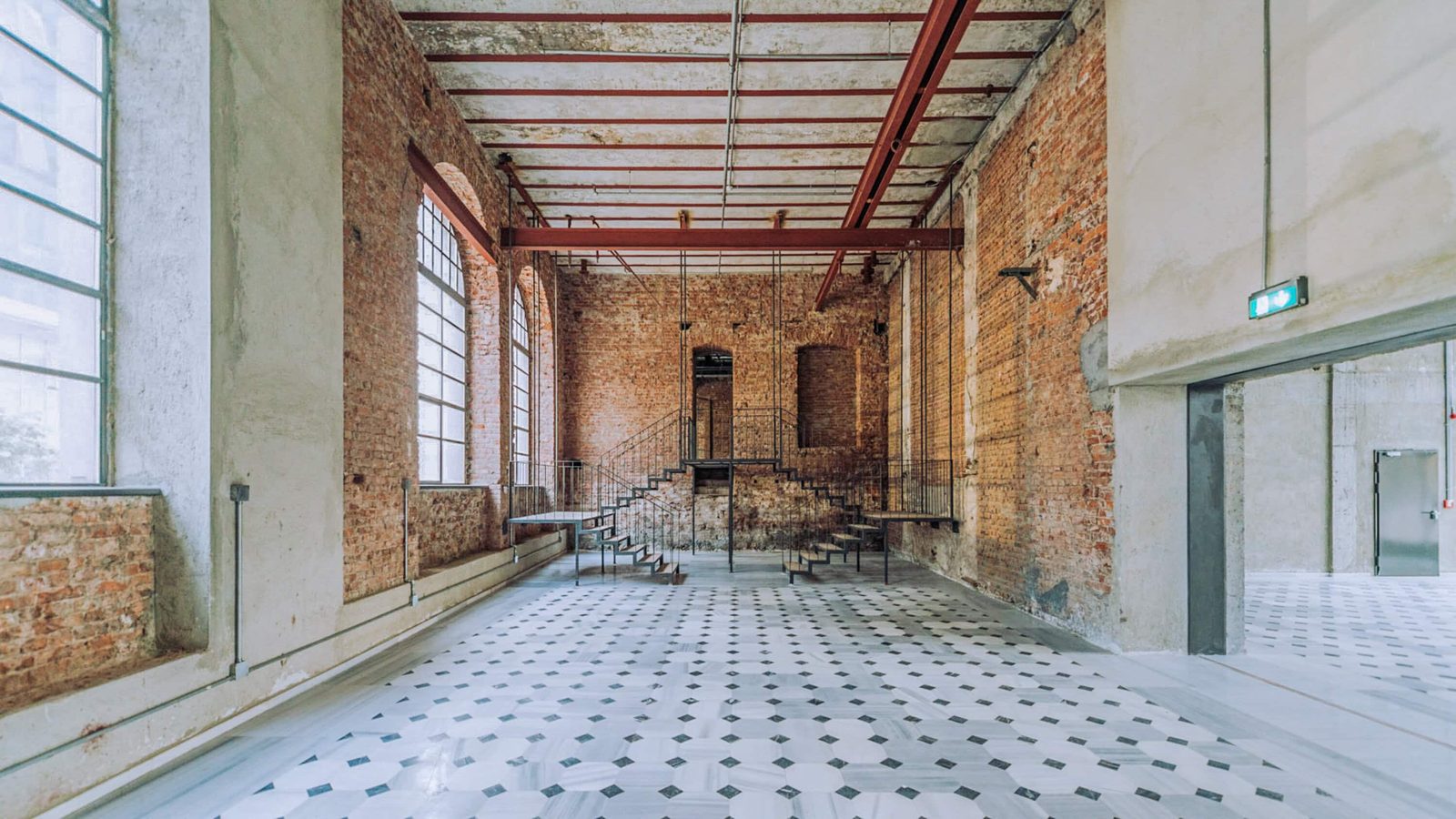 Restored brewery main hall with exposed brick walls and a patterned tile floor.