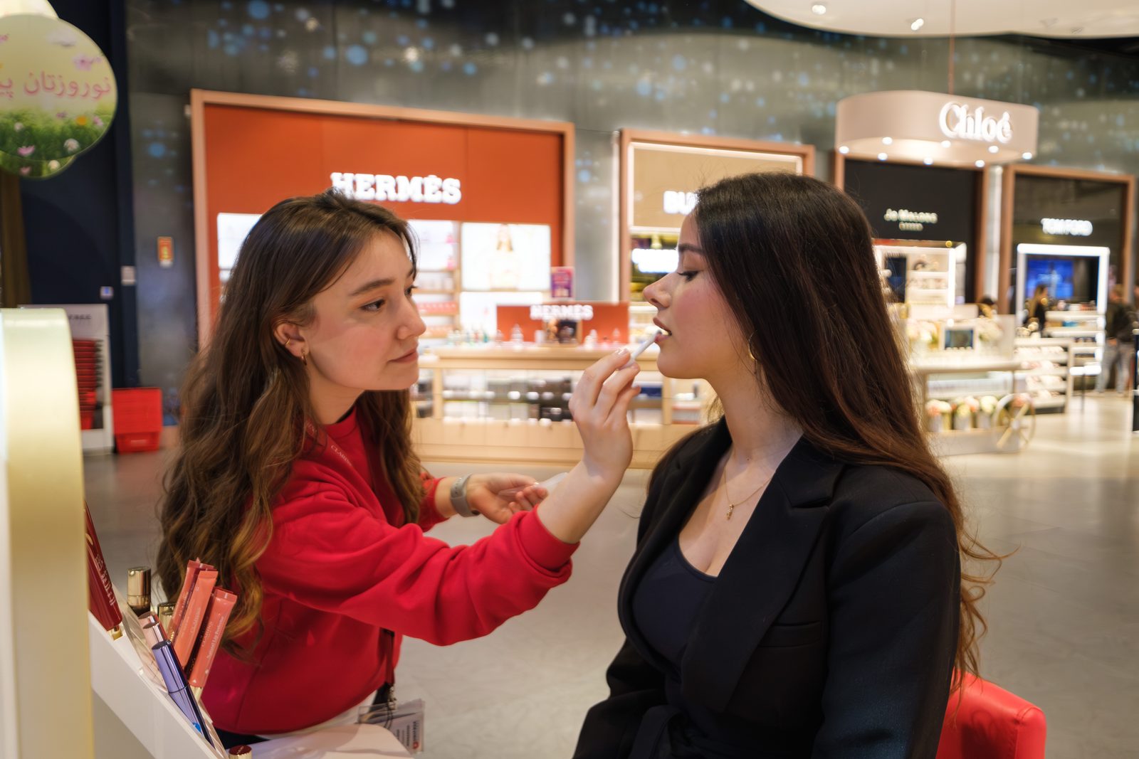 Clarins advisor applying lip colour to a guest at the brand counter in Istanbul Airport duty free.