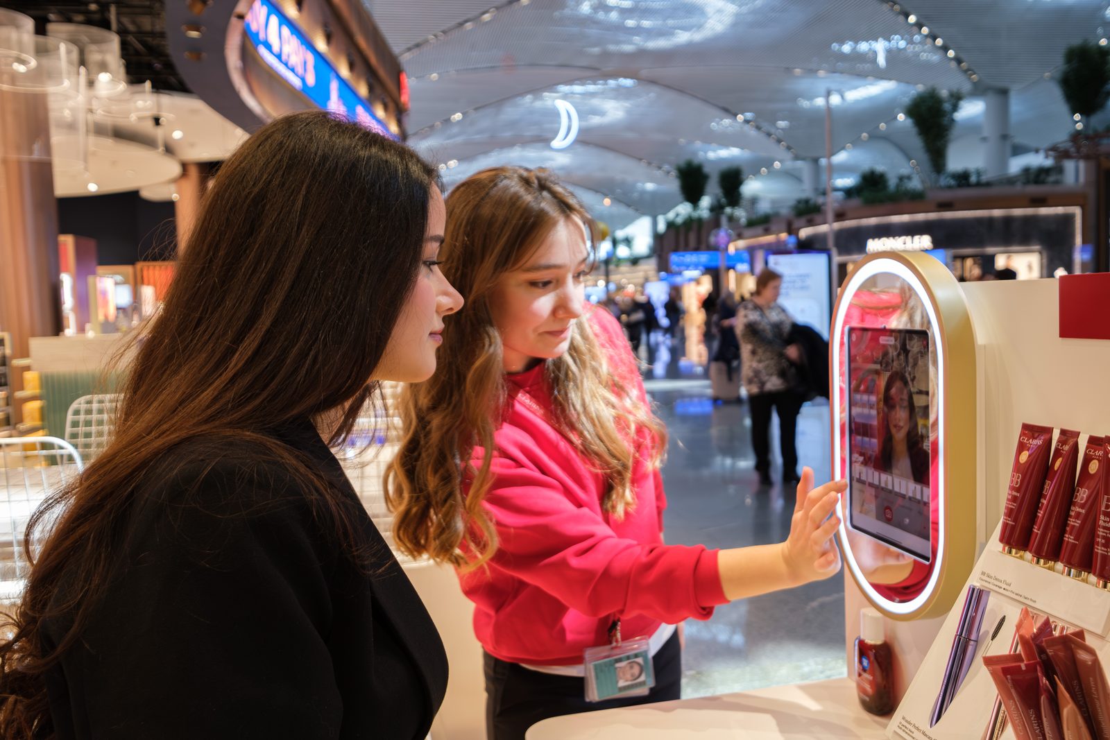 Clarins advisor guiding a guest through the virtual try on mirror at Istanbul Airport duty free.