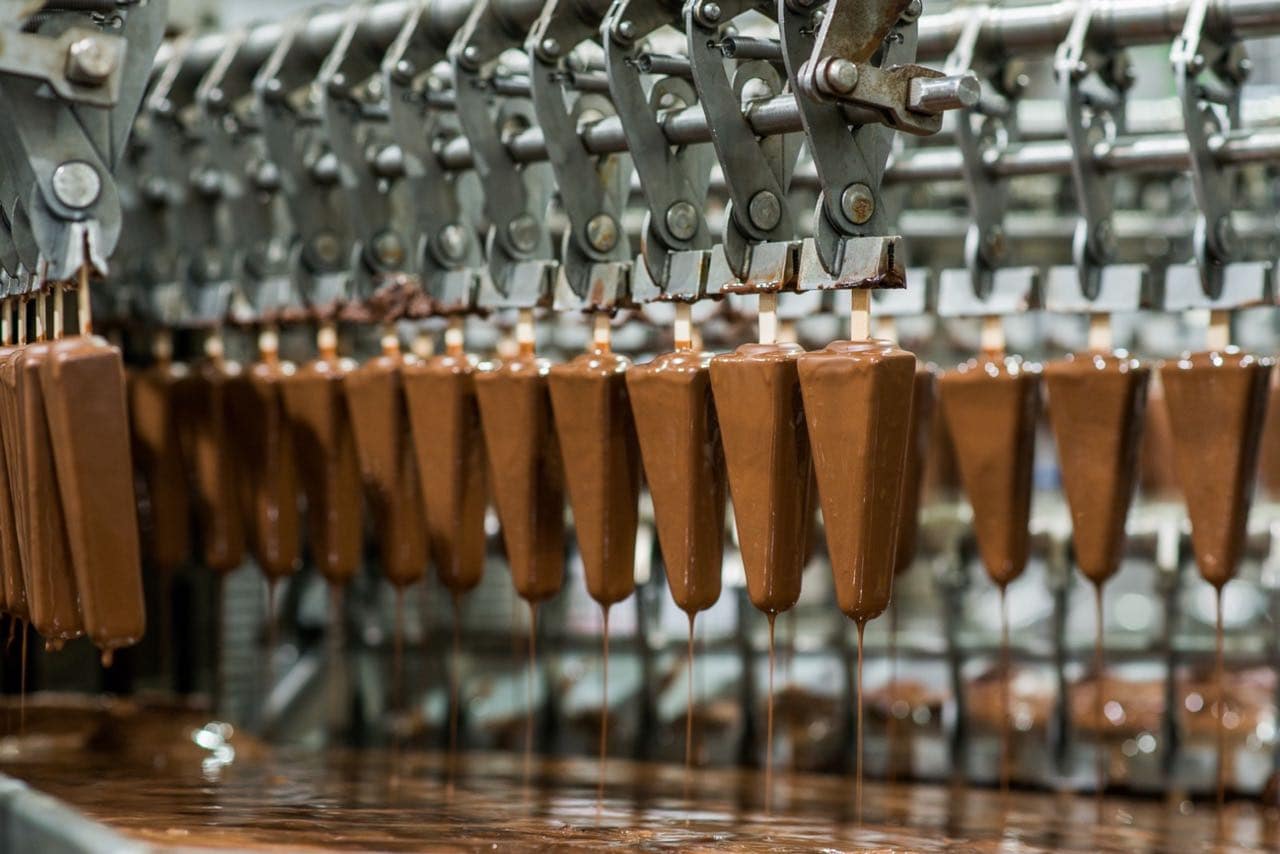 Chocolate coated cones travelling along an automated ice cream production line.