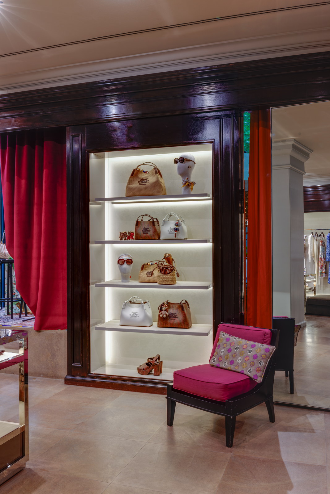 Estantes iluminados con bolsos y zapatos junto a una butaca en la boutique.