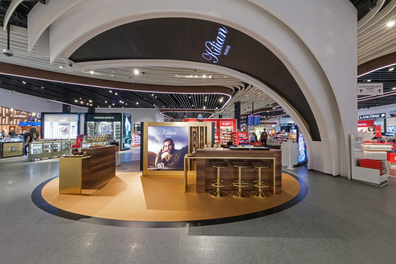 Kilian Paris fragrance bar under the curved white ceiling arch of an airport duty free store.