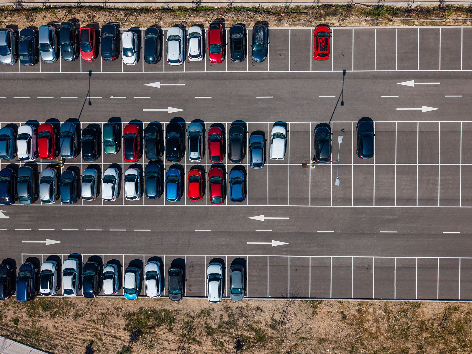 Top down aerial of a logistics park staff car park, marked bays and directional arrows on fresh asphalt.