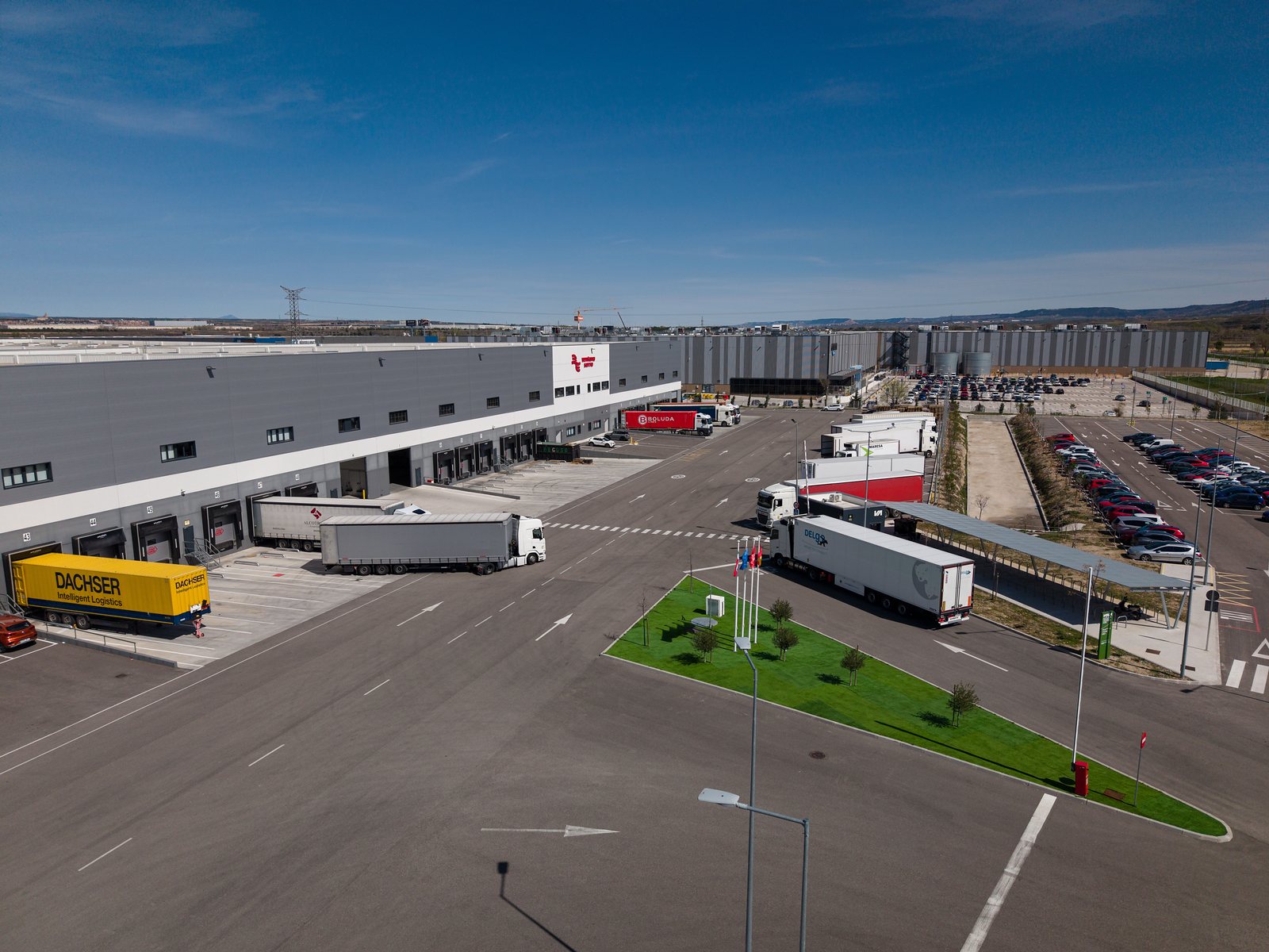 Aerial three quarter view of a warehouse dock face with articulated lorries at the bays and a wide manoeuvring yard.