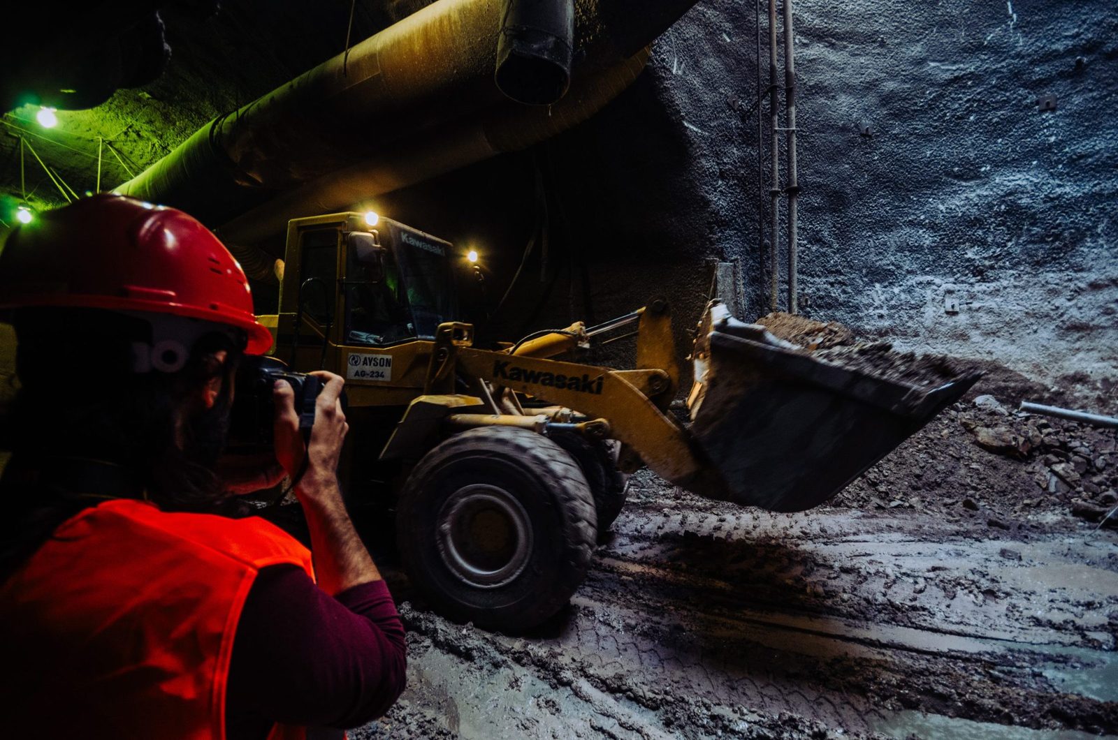 PRL-certified photographer documenting Istanbul metro construction in underground tunnel with heavy machinery, full PPE safety compliance, and active worksite hazards