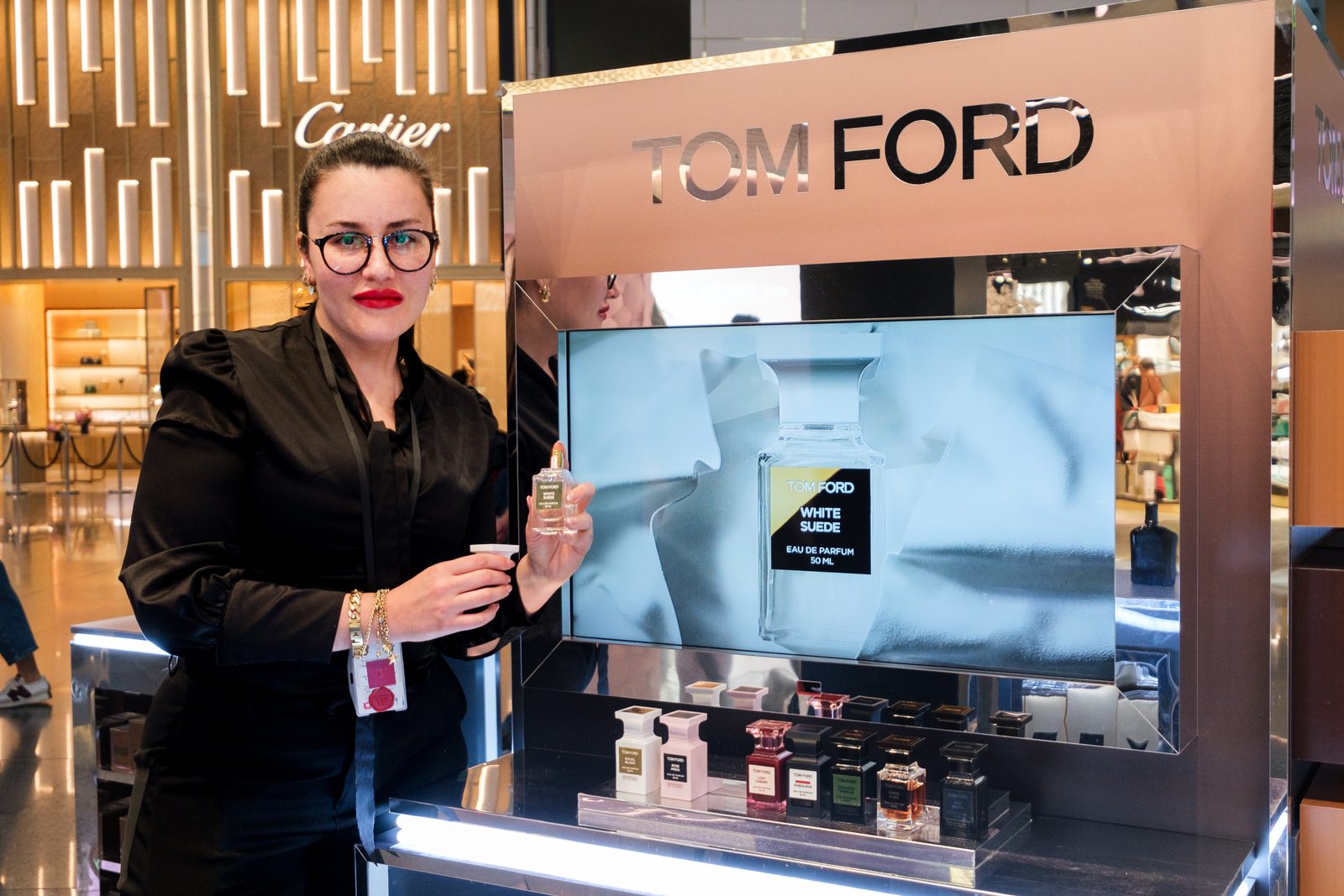 Tom Ford Beauty advisor presenting a fragrance beside a digital screen at Istanbul Airport duty free.