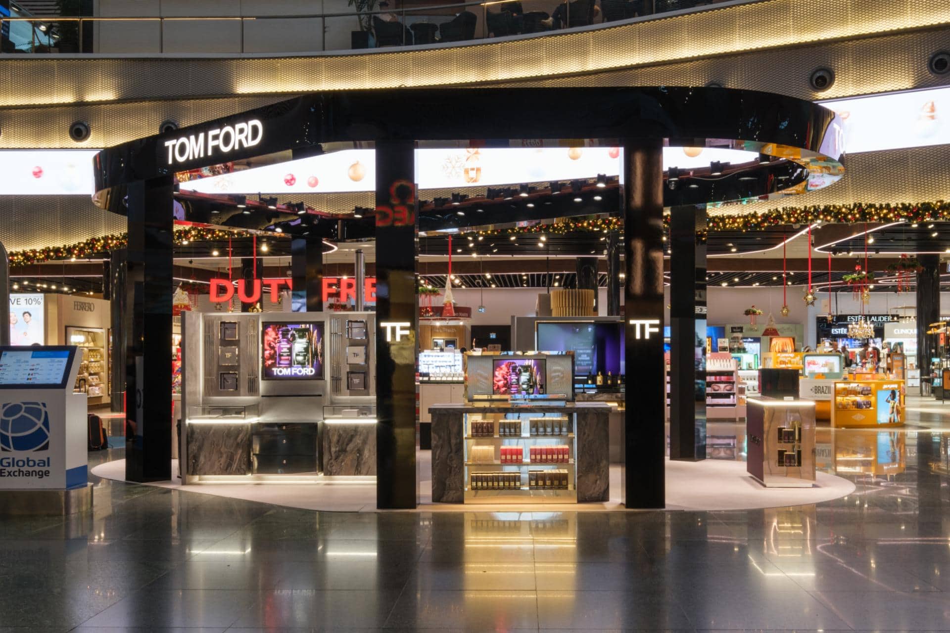 Tom Ford Beauty duty free kiosk in an airport terminal, black lacquer fixtures with digital brand screens.