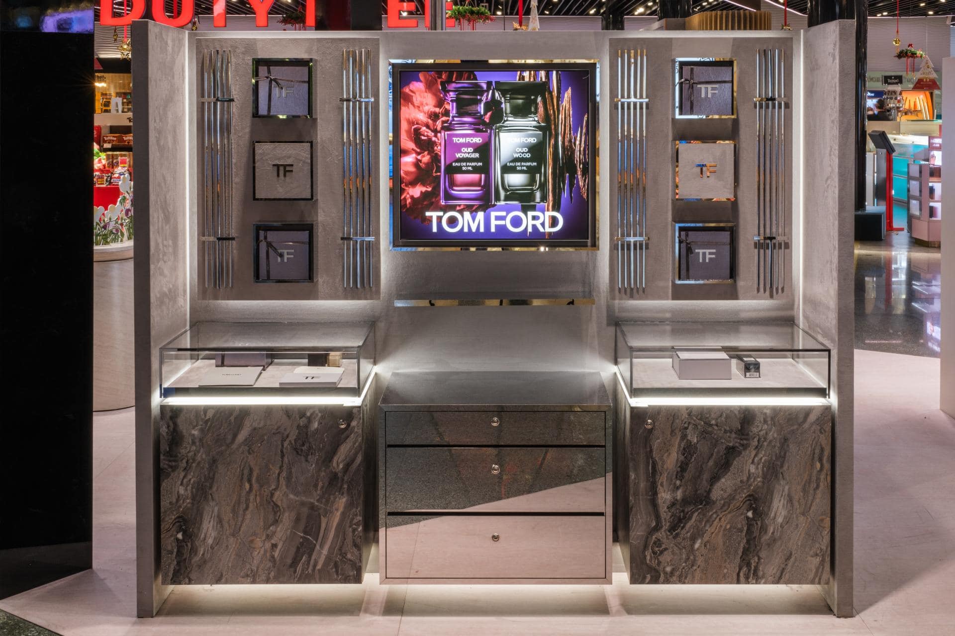 Tom Ford Oud Wood fragrance tray on an illuminated display unit inside an airport duty free store.
