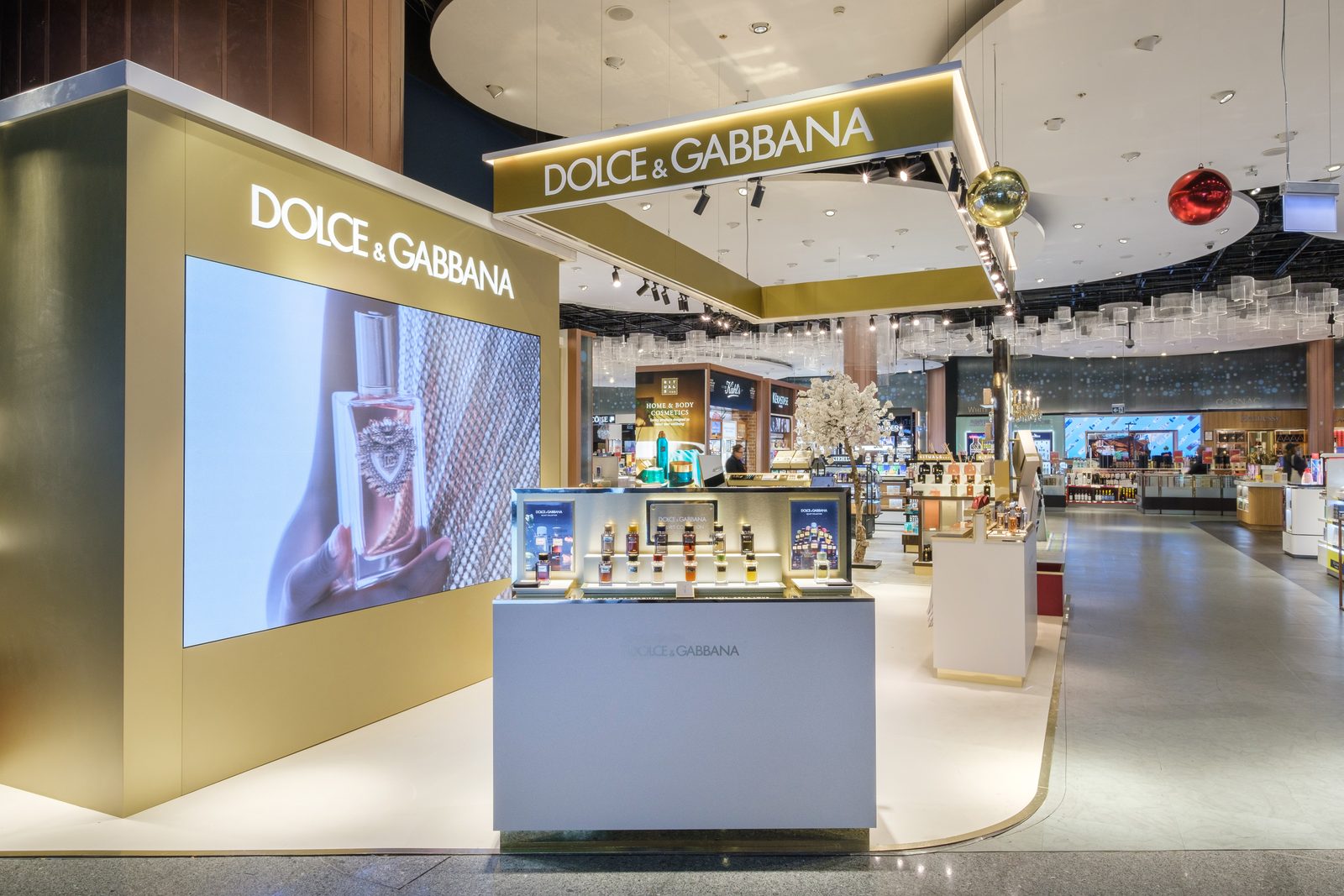 Dolce & Gabbana boutique entrance with a large video wall and fragrance counter in a duty free store.