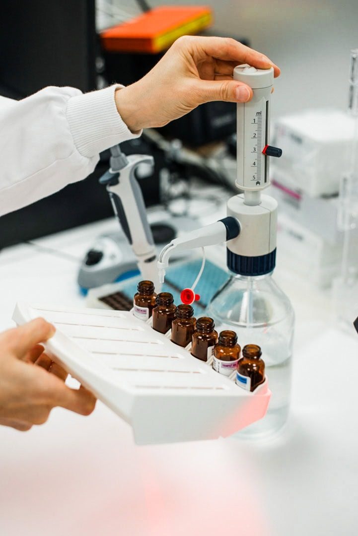 Pipette with liquid dropper and small brown bottles in laboratory setting.