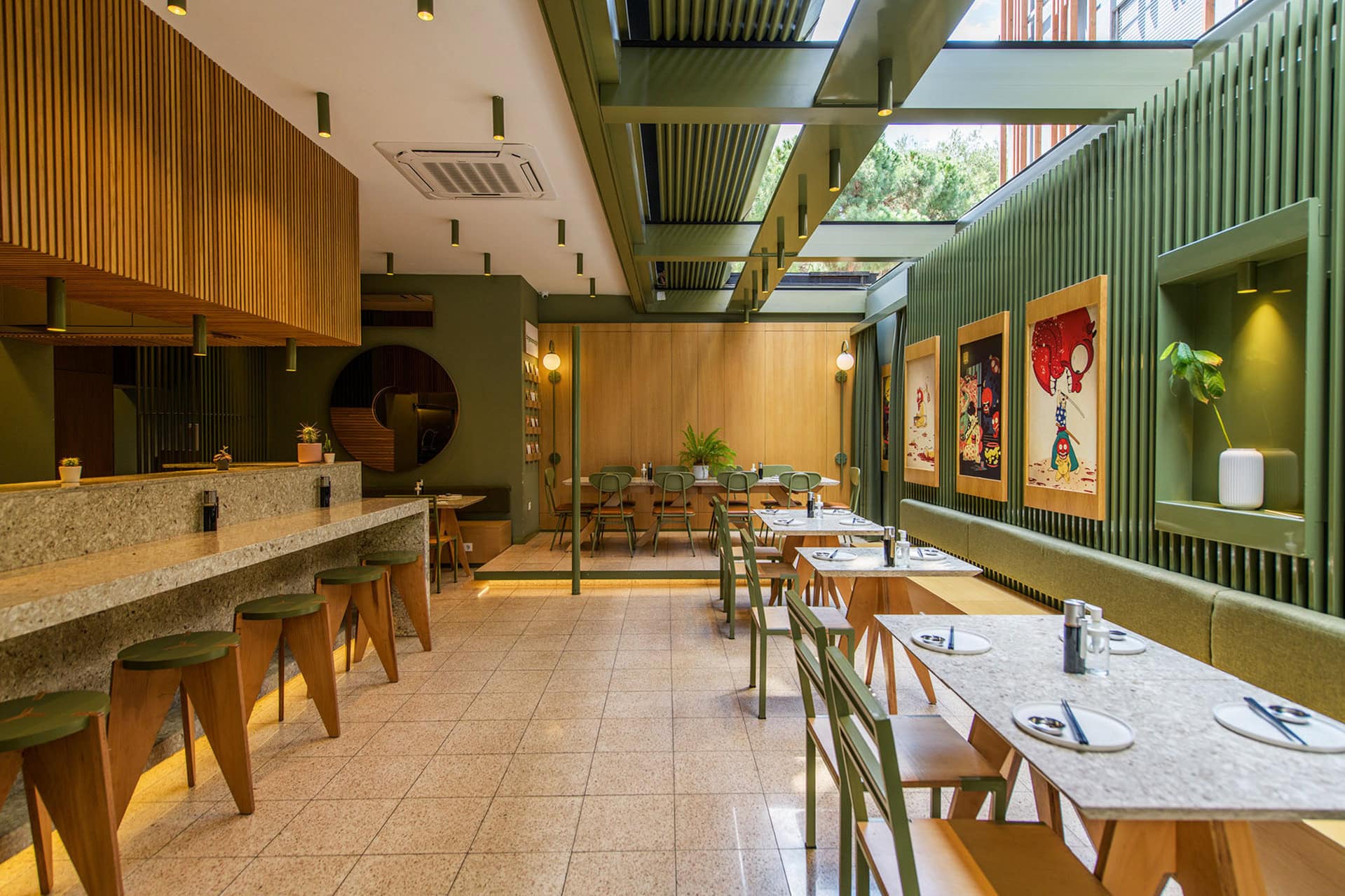 Contemporary restaurant interior with green accents, wooden furniture, and colorful artwork, showcasing modern hospitality design and ambiance.