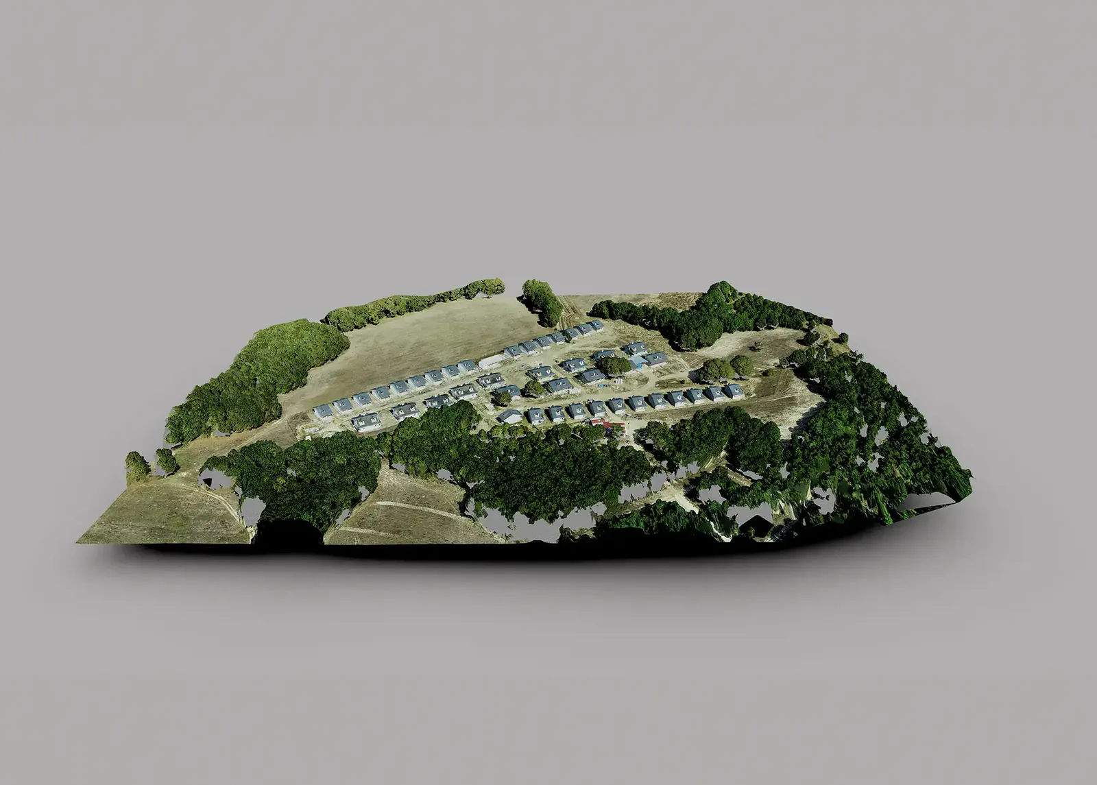 Photogrammetry model of a hillside site with rows of low buildings among trees.