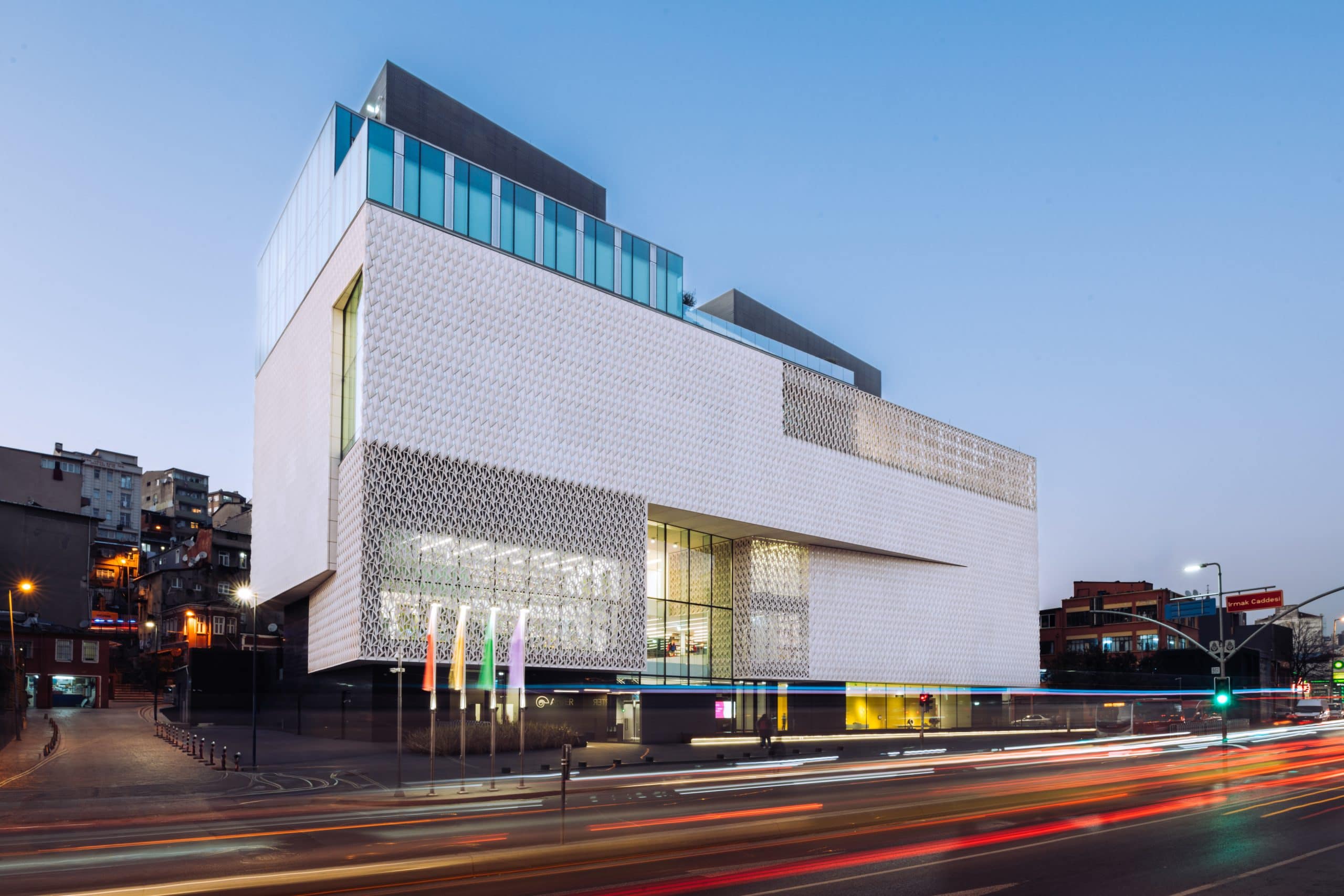 Edificio moderno contemporáneo en Madrid iluminado al anochecer que muestra el diseño arquitectónico con vibrantes luces y movimiento de la ciudad.