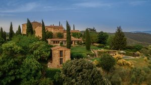 Luxurious Tuscan-style countryside villa surrounded by lush greenery, cypress trees, and scenic rolling hills in Spain, captured with professional architectural and landscape photography.