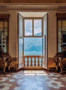 Luxurious open window with a mountain view in an elegant historic interior, featuring ornate furniture, detailed moldings, and classic design elements, showcasing architectural beauty and craftsmanship.