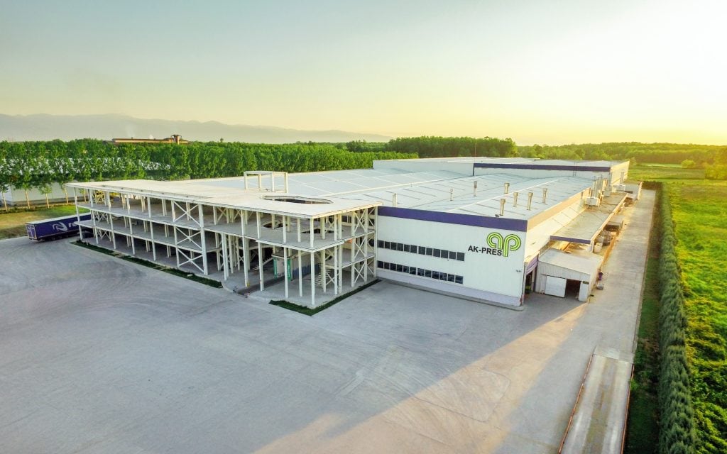 Aerial view of a modern industrial building with surrounding greenery and a bright, clear sky at sunset in Madrid, Spain.