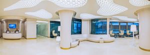 Reception area of a modern hotel with futuristic white furniture, distinctive ceiling design, large windows with views outside, and ambient lighting. The space exudes sleek, contemporary style ideal for hospitality photography.