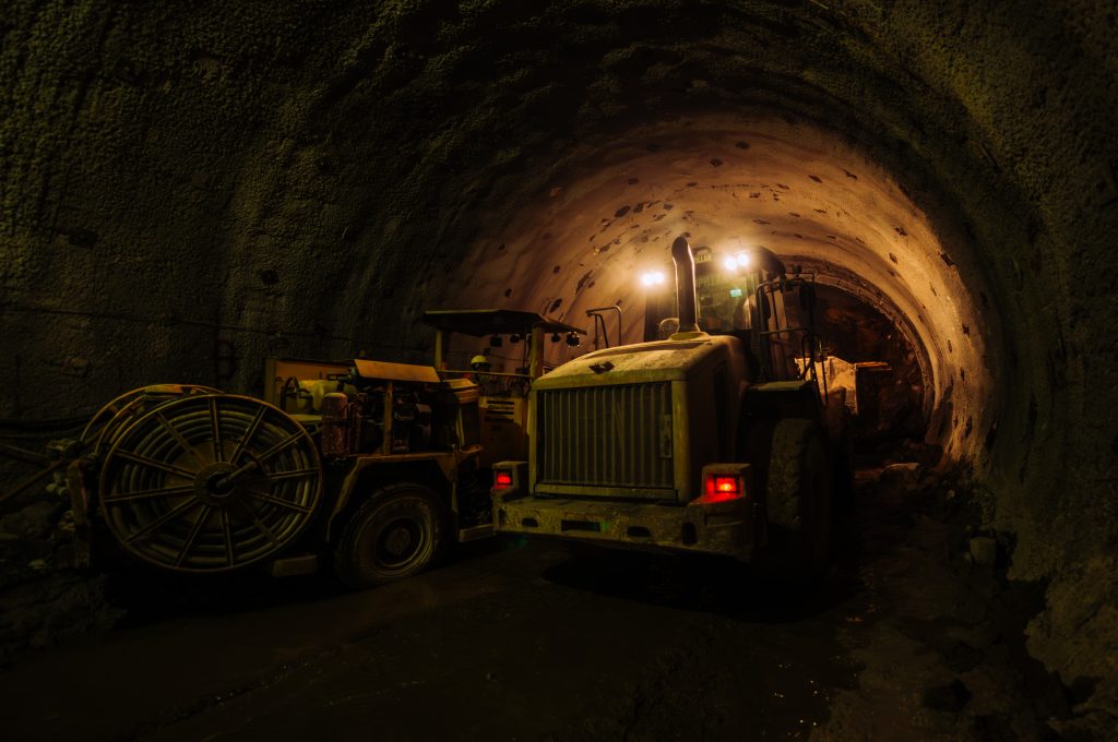 Drilling machine inside underground tunnel during construction at night.