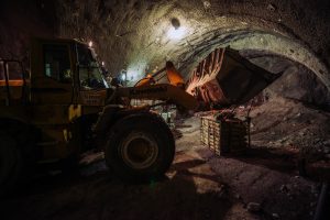 Kawasaki excavator working inside a tunnel construction site at night with artificial lighting.