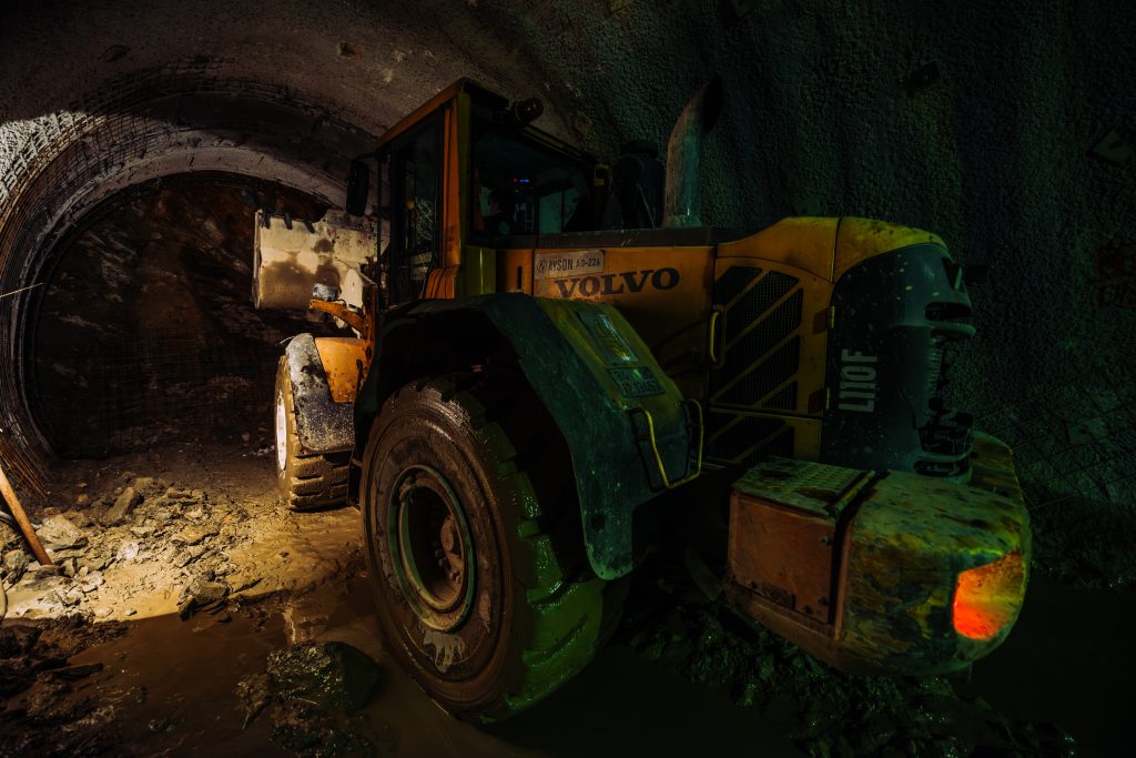 Volvo construction vehicle working inside a tunnel under dim lighting conditions.