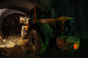 Volvo construction vehicle working inside a tunnel under dim lighting conditions.