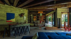 Modern interior of a stylish living room with wooden accents, large windows, colorful decor, and comfortable seating, showcasing contemporary design and cozy ambiance.