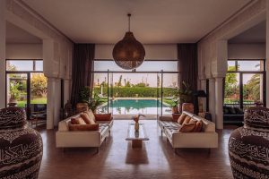 Luxury indoor living room with large glass doors opening to swimming pool and garden in Madrid Spain.