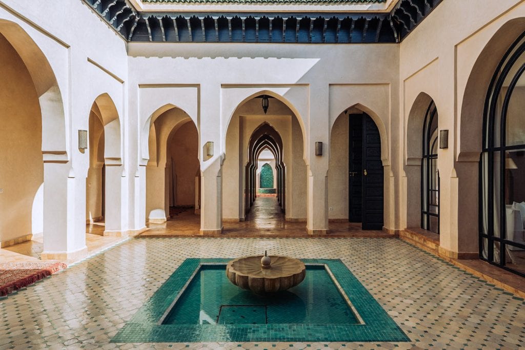 Elegant Moroccan-style interior courtyard featuring arches, intricate tile flooring, and a central fountain, captured for architectural and hospitality photography.