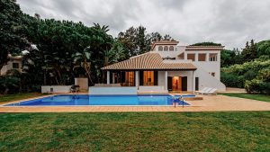 Modern house with a swimming pool, surrounded by lush greenery and tall trees, showcasing high-quality residential architecture with outdoor leisure space in Madrid.