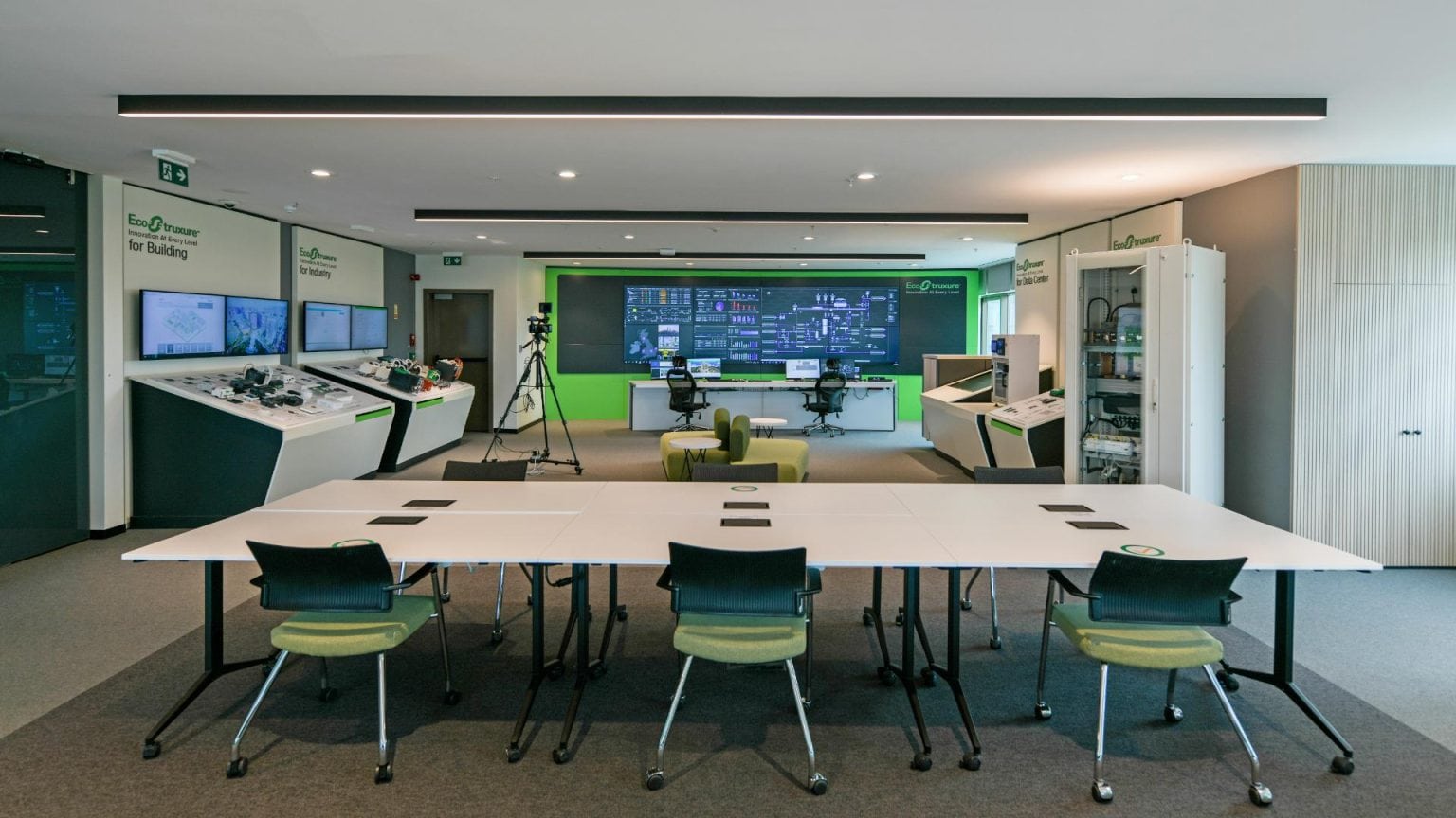 Modern control room with multiple screens and advanced technology for airport operations. Schneider Electric EcoStruxure experience center showroom overview. Corporate photography by TKM Photo, Madrid.