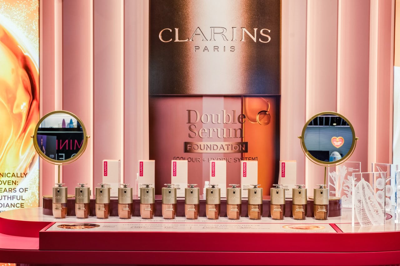 Display of Clarins Double Serum foundation bottles with branding and promotional materials in a professional setting.